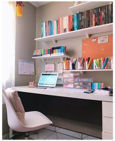 a desk with a laptop computer on top of it next to a book shelf filled with books