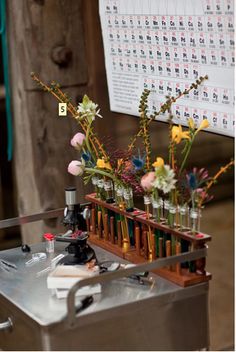 a metal table topped with lots of bottles filled with flowers