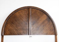 an arched wooden headboard against a white wall