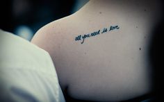 a person with a tattoo on their back saying, all you need is love