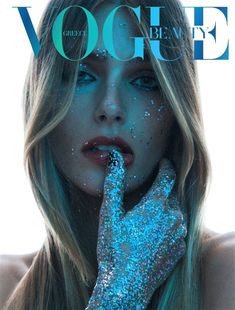 a woman with blue glitter on her face and hand over her mouth, posing for the cover of a magazine