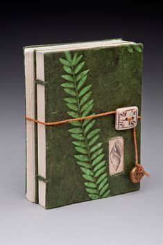 a book with a green leaf on the front cover and brown string attached to it