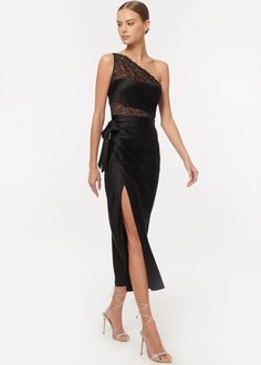 a woman wearing a black evening gown with an asymmetric slit