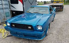 a blue car is parked in front of a trailer