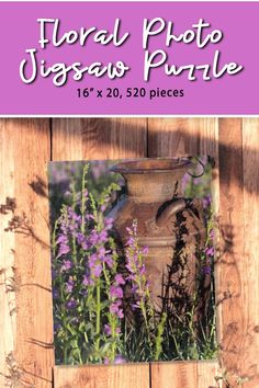 a vase sitting on top of a wooden fence with purple flowers in the foreground