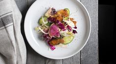 a white plate topped with assorted veggies on top of a wooden table