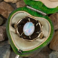 This fantastic vintage opal ring features a 4-prong set, oval cabochon opal at the center of a textured flower. The inside of the flower has been antiqued which really makes the opal pop. The ring is crafted in 14k yellow gold and is currently a size 6.5. This particular opal has a really nice play-of-color in red, green, blue, and violet. Luxury Vintage Oval Cabochon Opal Ring, Heirloom Oval Cabochon Opal Ring, Heirloom Oval Moonstone Ring, Heirloom Oval Opal Ring Collectible, Collectible Yellow Gold Opal Ring Oval Cabochon, Vintage Opal Cabochon Ring, Victorian Opal Cabochon Ring As Gift, Collectible Oval Cabochon Opal Ring In Yellow Gold, Victorian Cabochon Opal Ring For Gift