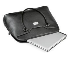 an open laptop computer sitting on top of a black leather bag next to a white laptop