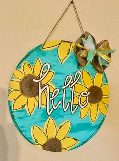 a blue sign with sunflowers and the word hello painted on it hanging from a wall