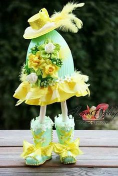 the doll is dressed in yellow and has flowers on her dress, boots and hat