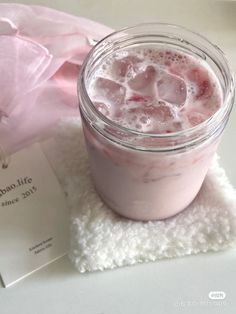 a pink drink in a glass with ice cubes on the rim next to a card