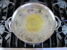 a frying pan filled with liquid on top of an oven burner next to two burners