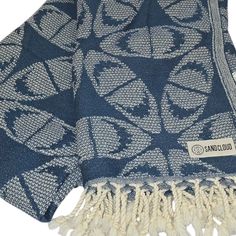 a blue and white patterned blanket with tassels