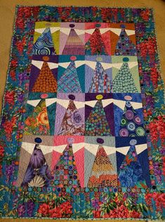 a quilted table top with many different designs and colors on the fabric, including trees