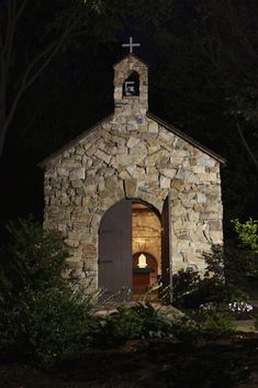 an old stone church with a cross on the front door and bell tower lit up at night