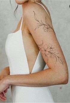 a woman with a flower tattoo on her arm and shoulder is looking at the camera