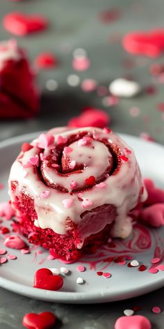 a piece of red velvet cake with white frosting and sprinkles on a plate