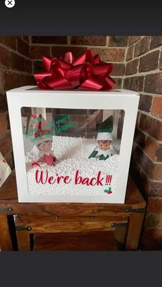 a white box with a red bow on top of it that says we're back