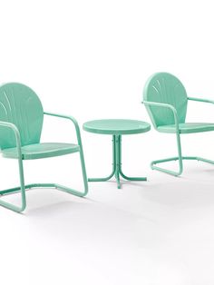 two green chairs and a small table on a white surface with one chair facing the other