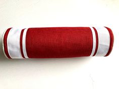 a red and white towel is hanging on the wall next to a toilet paper roll