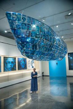 a woman standing in front of a giant blue object that is suspended from the ceiling