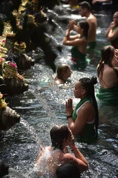 several people are in the water and one person is holding her hands up to their chest