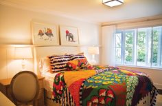 a bed with colorful blankets and pillows in a bedroom next to two lamps on either side of the bed