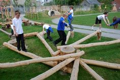 children playing in a play area made out of logs and wood sticks on the grass