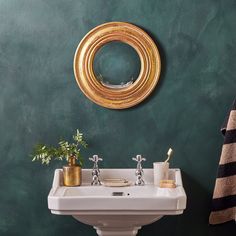 a white sink sitting under a mirror next to a green wall