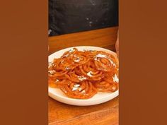 a white plate topped with pasta on top of a wooden table