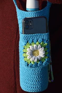 a cell phone in a crocheted case with a flower on the front and side