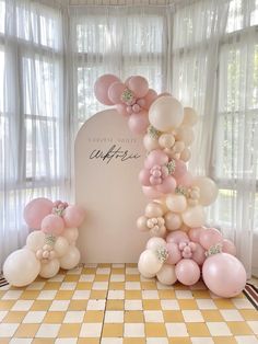 balloons are arranged in the shape of an arch with flowers and bows on it, along with other decorations