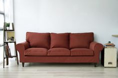 a living room with a red couch and bookcase on the floor next to a window