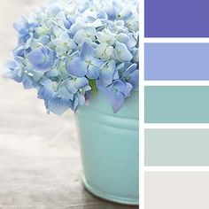 a blue flower pot filled with flowers on top of a wooden table next to color swatches