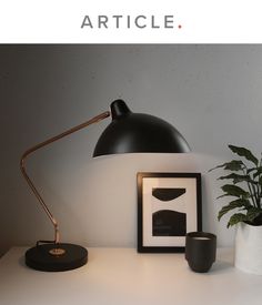 a white desk with a black lamp and some pictures on the table next to it