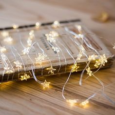 a wooden table topped with a book covered in stars and string lights on top of it