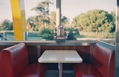 two red chairs sitting next to each other at a table in front of a window