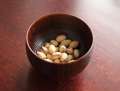 a wooden bowl filled with nuts on top of a table