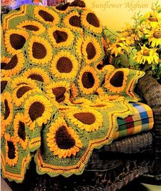 a sunflower afghan sitting on top of a wicker chair next to yellow flowers