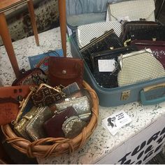 several pieces of luggage sitting on top of a table next to a basket with purses in it