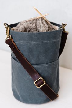 a gray bag with a brown leather strap