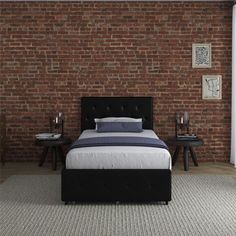 a bed sitting in front of a brick wall next to two end tables and lamps