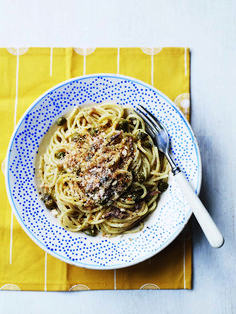 a white plate topped with pasta on top of a yellow and blue table cloth next to a fork