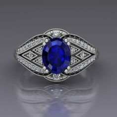 "A beautiful large oval blue sapphire is set in the center of this vintage style cocktail ring in 14k white gold with diamonds. The sapphire is set with double prongs and set off by diamond panels edges with cutouts. Vintage style milgrain beading lines the edges. The ring has a European shank to help stabilize it and the top measures about 13mm at the widest point. Blue Sapphire Dimensions9x7mm EnhancementHeated Carat Weight 2.6 ColorMedium to medium dark navy blue ClaritySlightly included CutGood PolishGood Diamonds Number40 EnhancementNatural Carat Total Weight0.31 ColorF-G ClaritySI1-2 CutVery Good PolishVery Good This is a custom made item! When you order, we will create a wax model of your ring with our 3D printer. This model is then cast in 14k gold, which is polished and set by han Vintage Blue Sapphire Ring, Clover Ring, Dream Engagement Rings, Emerald Engagement, Rhodolite Garnet, September Birthstone, Blue Sapphire Rings, Sapphire Jewelry, Best Diamond