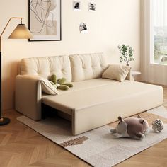 a living room with a couch, lamp and pictures on the wall above it in front of a window