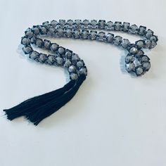 a long beaded necklace with tassels is shown on a white table top