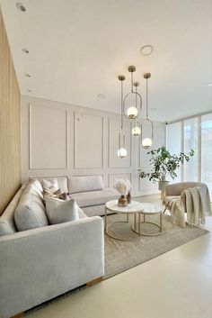 a living room filled with white furniture and lots of windows next to a large window