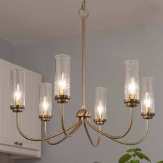 a chandelier with six lights hanging from it's center, in a kitchen