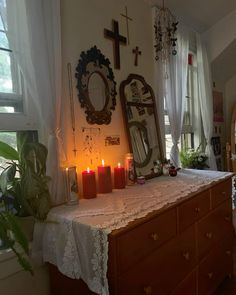 a table with candles on it in front of a mirror and cross above the dresser