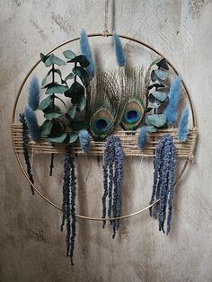 an arrangement of blue flowers and feathers on a circular rack with metal wire hanging from the wall